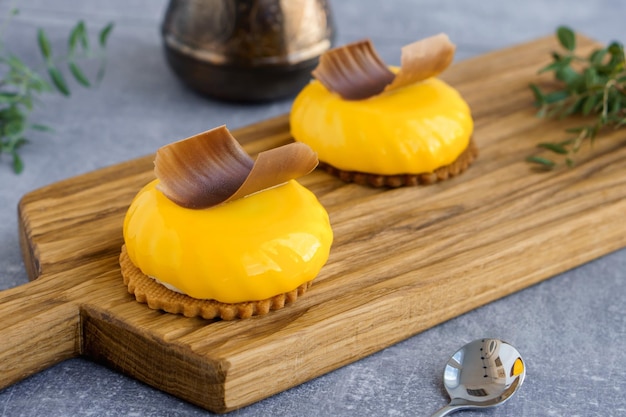 Słodki deser Żółte ciastka brzoskwiniowe z plasterkiem czekolady na wierzchu na drewnianej desce do krojenia i cezve