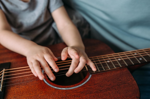 Słodki dzieciak bawi się w domu dużą gitarą akustyczną