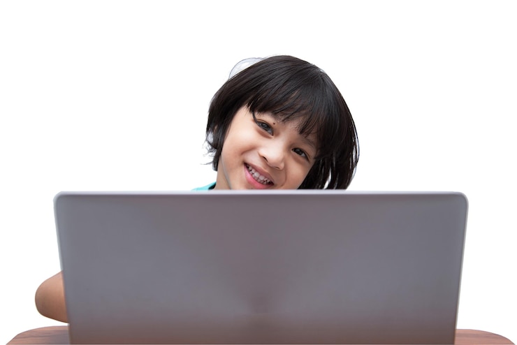 Słodki, inteligentny azjatycki chłopiec szczęśliwie używa swojego laptopa do samodzielnej nauki online w domu Koncepcja uczenia się onlineSamokształceniebiałe tło ze ścieżką przycinającą