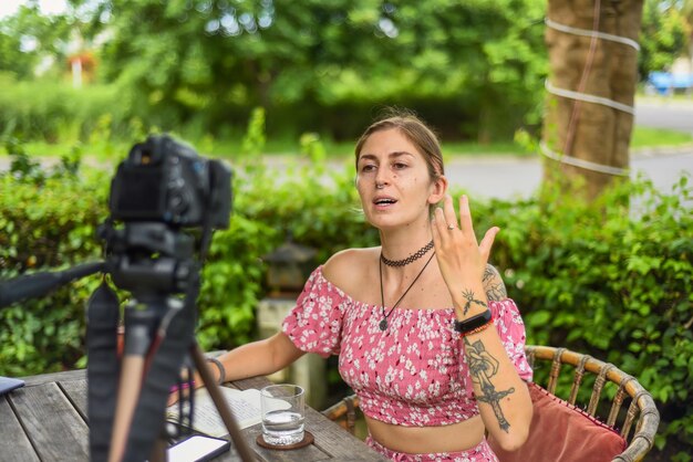 Zdjęcie słodki kamerzysta i vlogger nagrywający wideo z kamerą i statywem w letnim ogrodzie