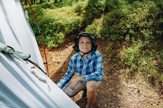 Słodki, kaukaski chłopiec rozstawiający koncepcję rodzinnego biwakowania w namiocie