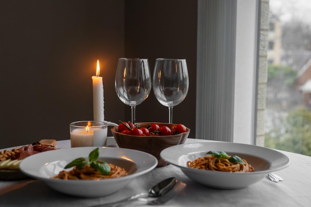 Zdjęcie słodki makaron bolognajski z basilikiem, prosciutto, serem i orzechami, zestaw stołowy z pomidorami.