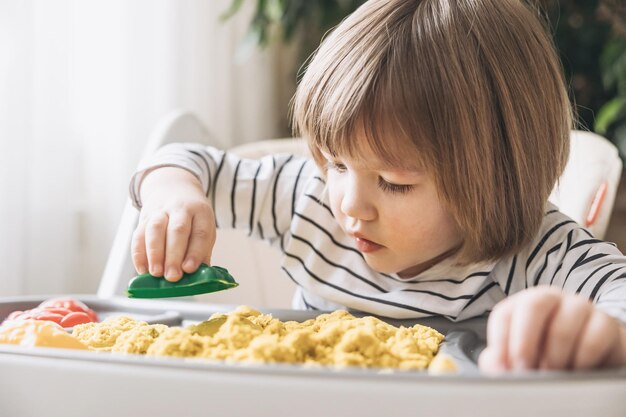 Słodki mały chłopiec bawi się piaskiem kinetycznym Rozwój umiejętności motorycznych Wczesna edukacja sensoryczna Zajęcia Montessori Zabawy sensoryczne w domu