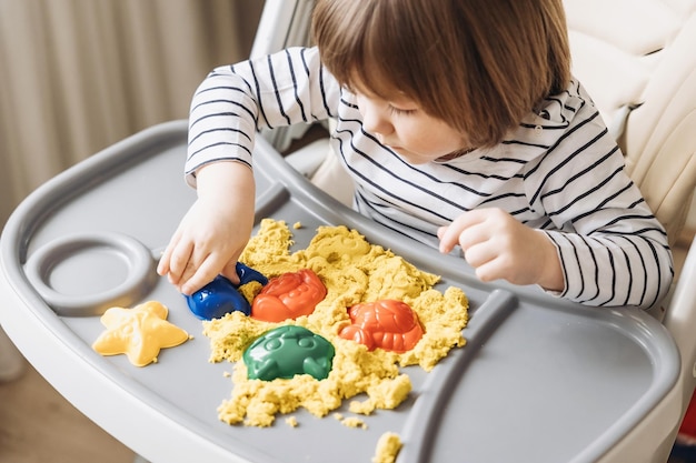 Słodki mały chłopiec bawi się piaskiem kinetycznym Rozwój umiejętności motorycznych Wczesna edukacja sensoryczna Zajęcia Montessori Zabawy sensoryczne w domu