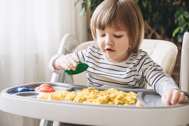 Słodki mały chłopiec bawiący się piaskiem kinetycznym Rozwój umiejętności motorycznych Wczesna edukacja sensoryczna Zajęcia Montessori Zabawy sensoryczne w domu