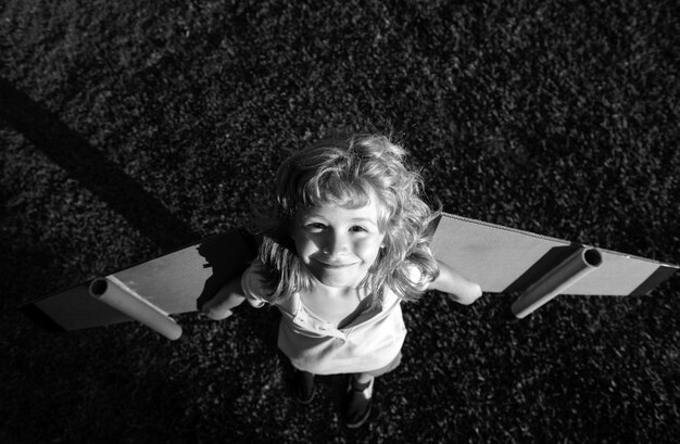 Słodki marzyciel bawiący się kartonowym samolotem dziecięca wyobraźnia
