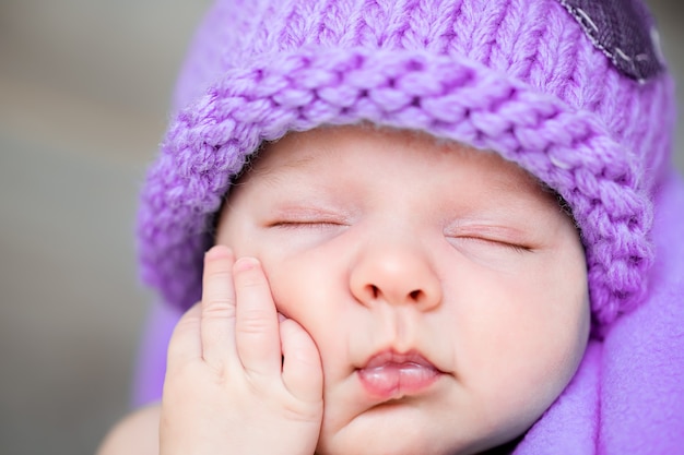 Słodki sen noworodka w fioletowej czapce