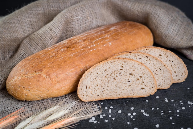 Słodki smaczny chleb i pszenica na drewnianym tle
