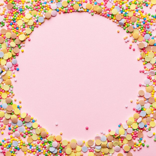 Zdjęcie słodkie ciasto składnik ciasta. cukrowa posypka do pieczenia w kształcie koła. okrągła rama z polewą do ciasta. pusty projekt w centrum. na białym tle na różowym tle. koncepcja wakacje i urodziny.