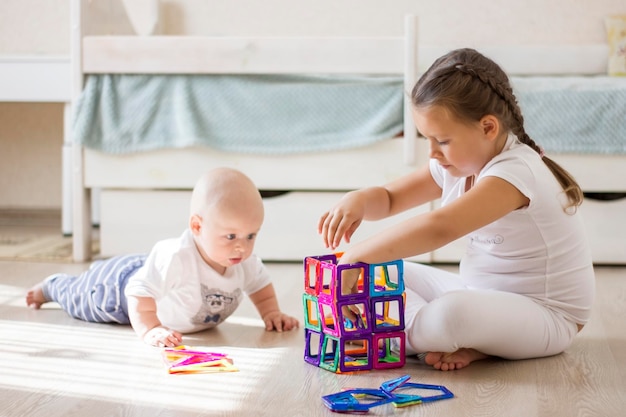 Zdjęcie słodkie dzieci niemowlę chłopiec i mała dziewczynka bawią się zabawkami magnetycznymi w domu