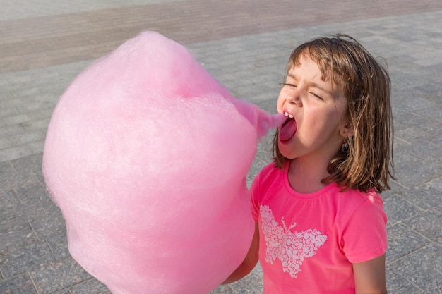 Zdjęcie słodkie dziecko zjada ulicę z różowej sacharyny w słoneczny dzień sweets