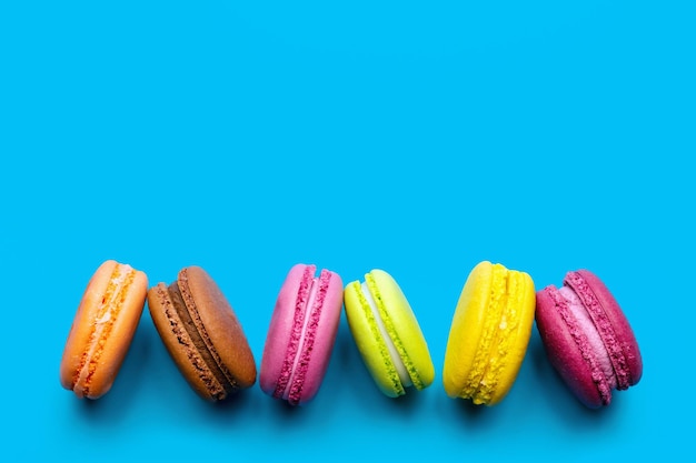 Słodkie i kolorowe francuskie makaroniki na niebieskim tle