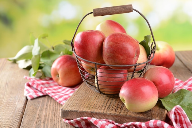 Słodkie jabłka w wiklinowym koszu na stole na jasnym tle