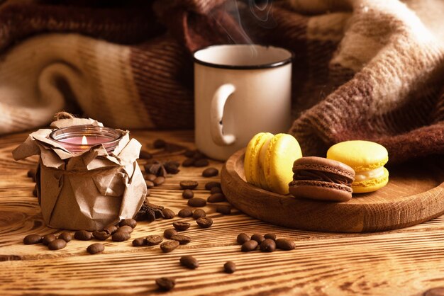 Słodkie makaroniki na drewnianej desce z filiżanką kawy i płonącą świecą Atmosferyczne zdjęcie Zawartość dla sieci społecznościowych