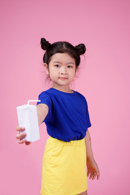 Słodkie pewnie azjatyckie małe dziecko dziewczynka pić mleko pudełko