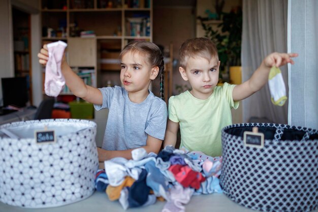 Słodkie rodzeństwo trzymające brudne ubrania w domu