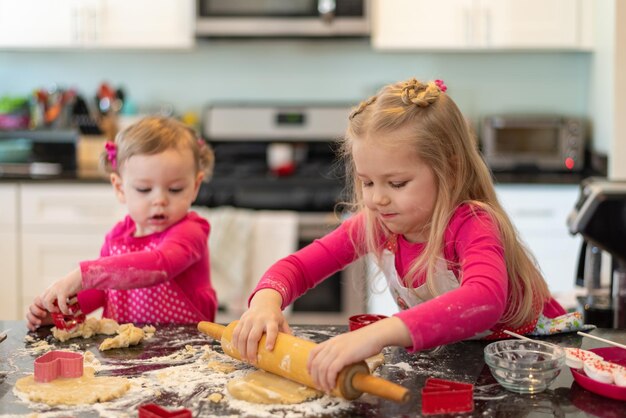 Zdjęcie słodkie siostry robią ciasteczka na wyspie kuchennej.