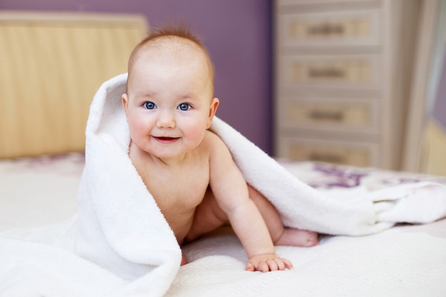 Słodkie uśmiechnięte dziecko patrzące pod biały ręcznik na białym tle