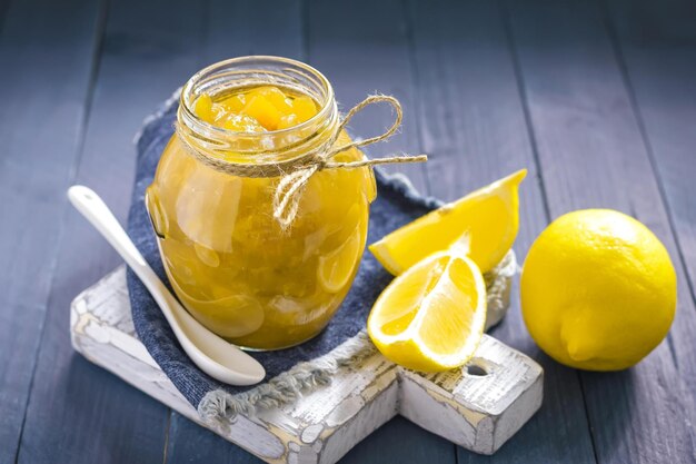 Zdjęcie słoik lemon curd stoi na niebieskim drewnianym stole.