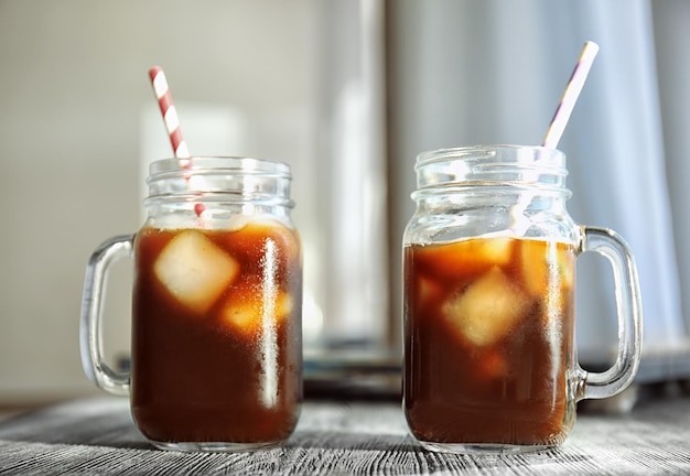 Słoiki Mason z kawą cold brew i słomkami na drewnianym stole