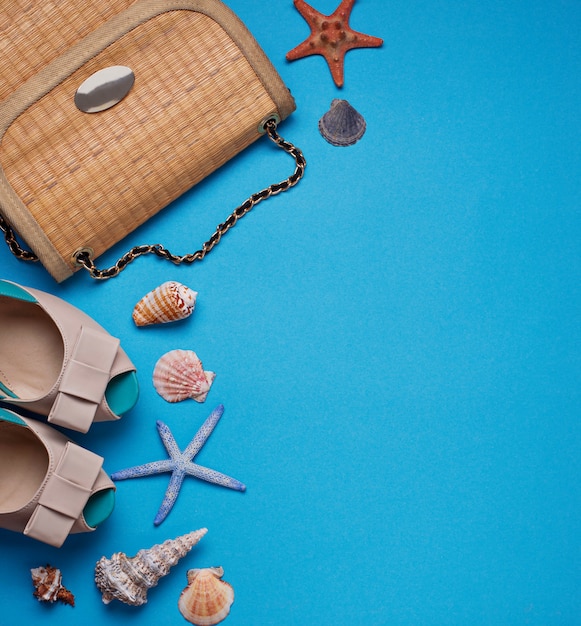 Słomiana torba, buty i seashells na błękitnym tle