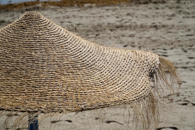 Słomiany parasol na piaskowatej plaży zbliżenie