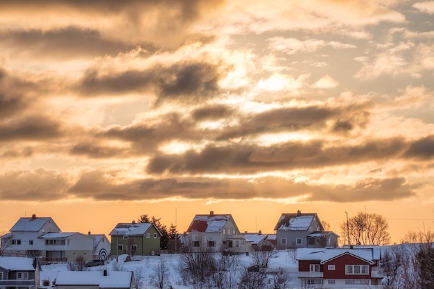 Słońce w chmurach nad skandynawską wioską rybacką ze śniegiem w zimie