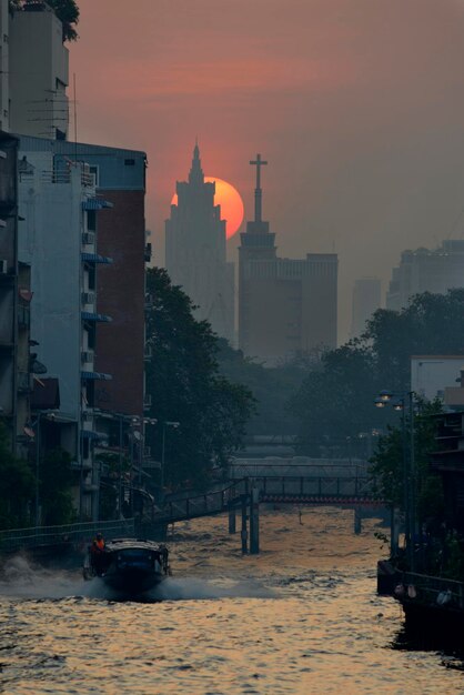 Słońce wschodzi za wieżowcem nad kanałem Bangkok, Tajlandia