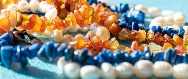 Zdjęcie słoneczne koraliki z bursztynowej perły lapis lazuli na niebieskim tle naturalne morze kamień szlachetny koncepcja biżuterii w tle światła słonecznego