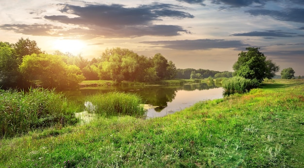 Słoneczny zachód słońca nad spokojną rzeką w lesie