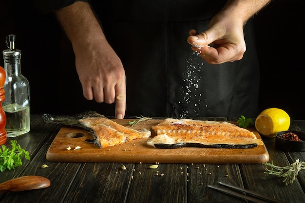 Słony kuchenne steki rybne na stole kuchennym Kuchnia amerykańska Proces przygotowywania ryb rękami szefa kuchni w restauracji lub hotelu kuchnia