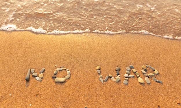 Słowa wypisane na piasku na plaży Słowa Bez wojny i napisane na piasku