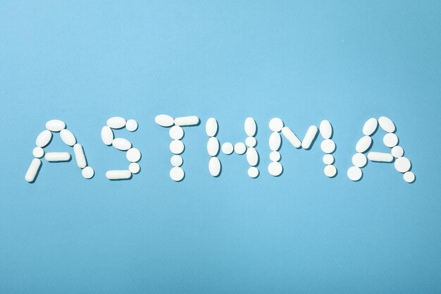 Słowo Astma z pigułek na niebieskim tle