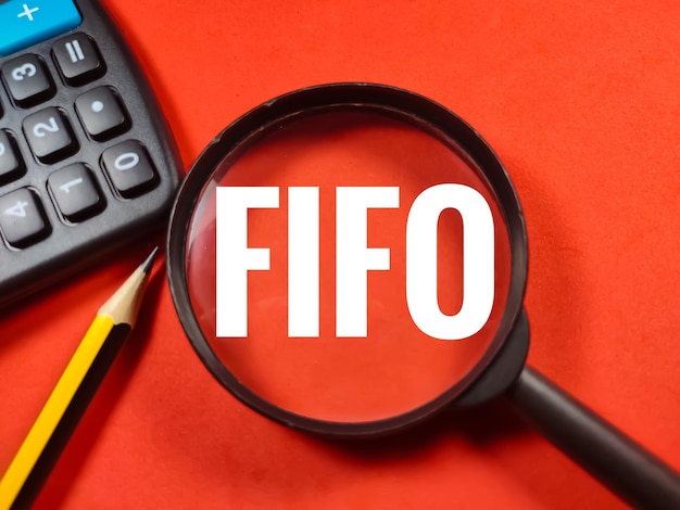 Słowo FIFO pierwsze weszło pierwsze wyszło z lupą, ołówkiem i kalkulatorem na czerwonym tle