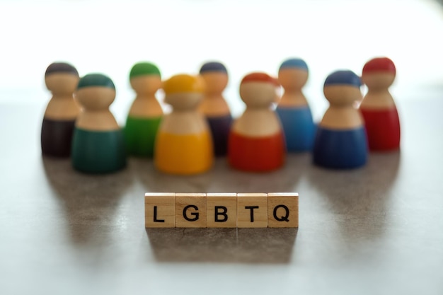 Słowo LGBTQ na drewnianych klockach z różnymi ludźmi w tle