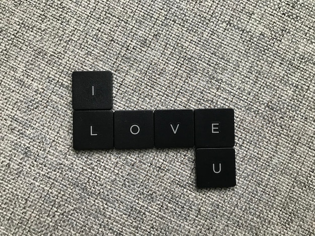 Słowo miłości wykonane z czarnych plastikowych płytek na szarym tle dywanu