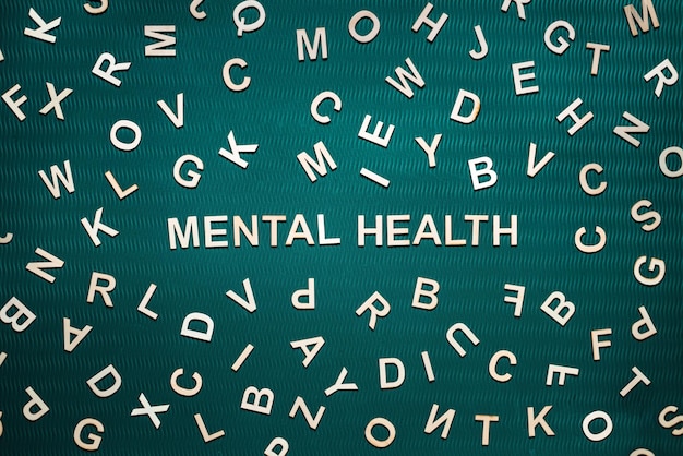 Słowo o zdrowiu psychicznym z drewnianych liter tekst o zdrowiu psychicznym na zielonym tle z wieloma innymi