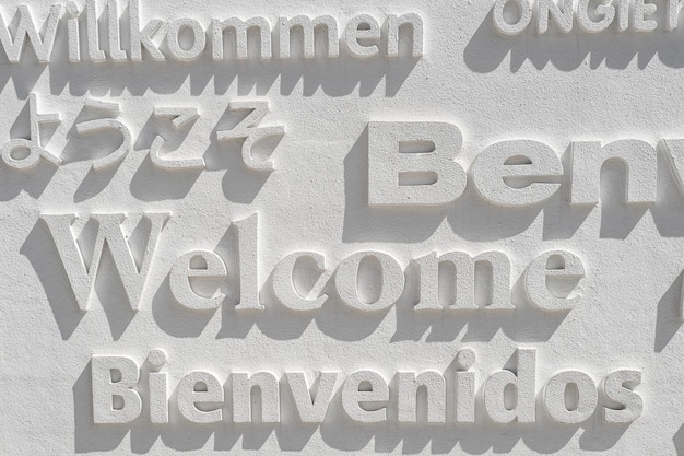Zdjęcie słowo powitalne napisane w kilku językach na białej ścianie