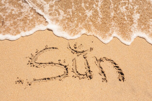 Słowo Słońce napisane na piasku na plaży