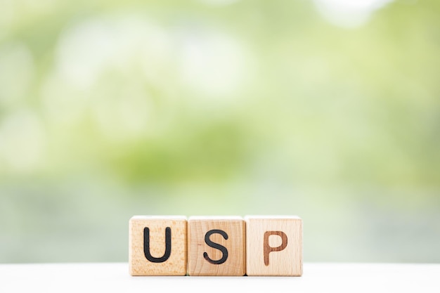 Słowo USP jest napisane na drewnianych kostkach na zielonym tle lata Zbliżenie elementów drewnianych