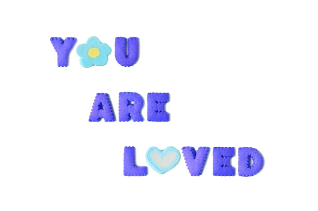 Zdjęcie słowo you are loved zapisane jest w żywych niebieskich ciasteczkach z alfabetu i pianki