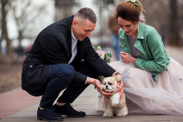 Ślub pary młodych ludzi. Są szczęśliwi i młodzi i cieszą się tym dniem ze swoim uroczym psem. Zmysłowe zdjęcie kochającej pięknej dziewczyny i przystojnego faceta.