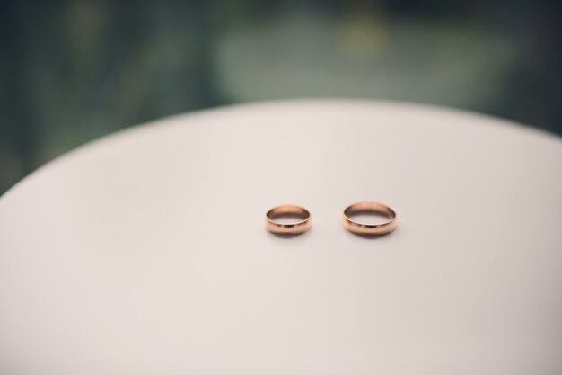 Ślubne diamentowe złote pierścienie pierścionki zaręczynowe na białym stole.