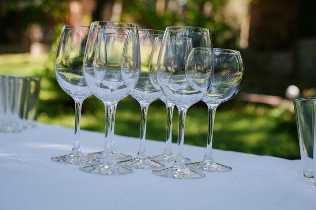 Ślubne kieliszki do szampana stoją na stole, na białym obrusie w ogrodzie. ślub.