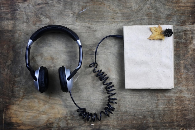 Słuchawki audiobookowe i książka na drewnianym stole
