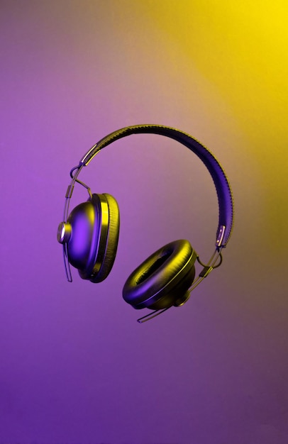Słuchawki lewitujące na wielokolorowym podświetlonym tle Bezprzewodowe przesyłanie muzyki podcast
