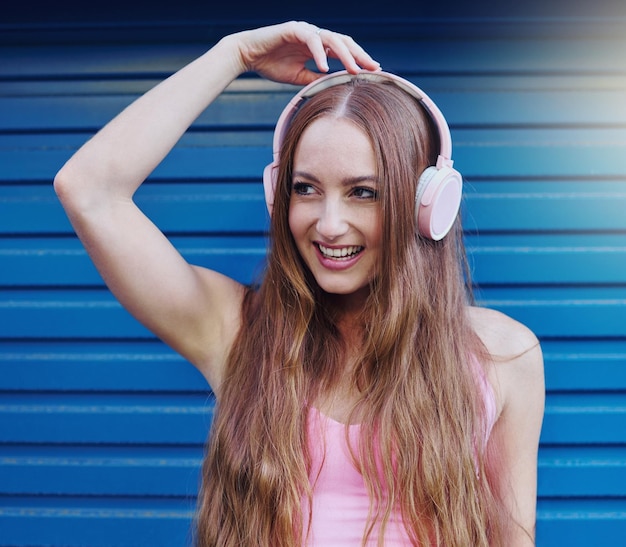 Słuchawki muzyczne i niebieskie tło z kobietą słuchającą lub przesyłającą strumieniowo dźwięk dla zabawy Internet radiowy i 5g z atrakcyjną młodą kobietą korzystającą z technologii bezprzewodowej do słuchania piosenki