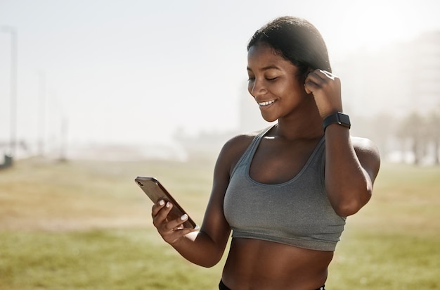 Słuchawki muzyczne lub telefon czarnej kobiety do podcastów fitness, motywacji do ćwiczeń lub radia treningowego na sportowym boisku Uśmiech szczęśliwa i mobilna technologia dla danych zdrowotnych sportowca lub treningu w aplikacji 5g