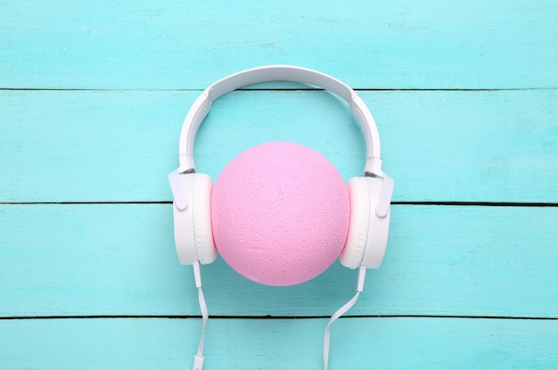 Słuchawki noszone na różowej piłce na niebieskim drewnianym tle Kreatywny układ Minimalizm koncepcja muzyki