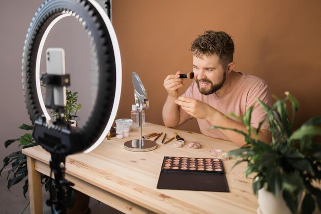 Słynny bloger Wesoły męski vloger pokazujący produkty kosmetyczne podczas nagrywania wideo i udzielający porad na swoim blogu o urodzie Wizażystka i nagrywająca koncepcję vloga o urodzie